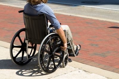 A man in a wheelchair rolling onto a brick walkway
