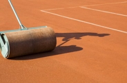 A Baltimore asphalt technician performing maintenance on a clay tennis court
