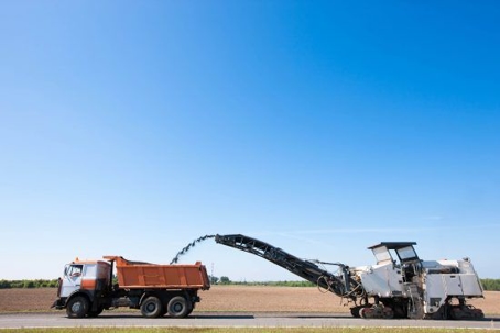 A machine disposing of asphalt into a dump truck