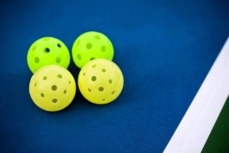 Two neon green and two neon yellow Wiffle balls