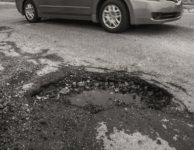 A car next to a pothole filled with water
