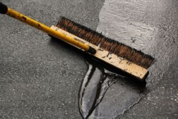 A brush applying asphalt sealant