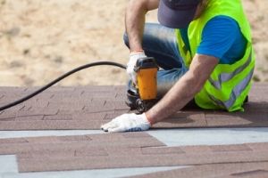 Asphalt contractor installing asphalt shingles on a new house
