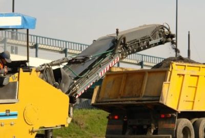 A machine disposing of asphalt into a dump truck