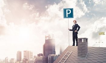 Businessman holding parking sign on the top of a roof