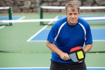 A man in a blue shirt on a Pickleball court