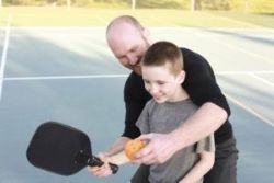 A man teaching his son how to play Pickleball