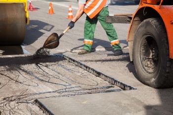 A contractor patching asphalt