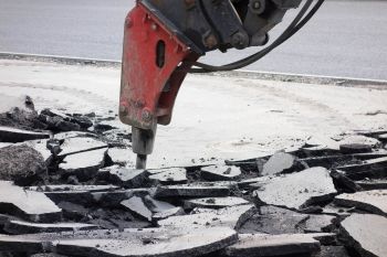 A motorized jackhammer drilling into asphalt to do full scale repairs