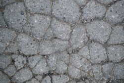 Close up of deep surface cracks on tennis court asphalt - How Often Do Tennis Courts Need Resurfacing?